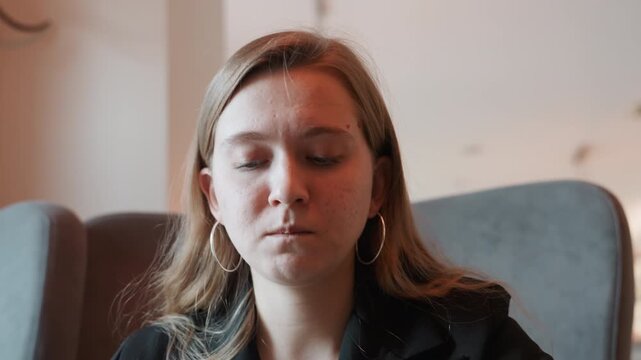 White woman tasting bitter medicine indoors executive in hotel lounge picks up pill, winces, covers mouth, closeup portrait under natural light capturing shock and uneasy expression