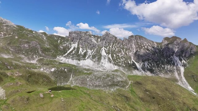 Cinematic aerial drone shot starting the flight over dramatic rugged limestone mountain peaks, rocky slopes, and a small alpine lake in Obernberg am Brenner, Austria.⁠