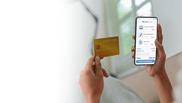 Cropped hands holding credit card and smartphone with shopping cart app for checkout