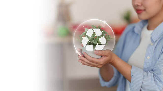 Asian woman holding potted plant with recycling icon for environmental sustainability concept
