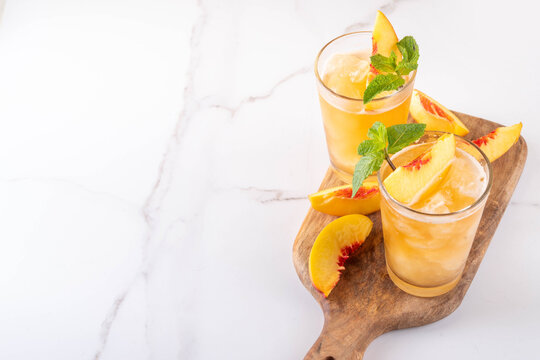 Summer cold drink, peach iced tea slushie cocktail. Shaved ice non-alcohol cold beverage, peach juice infused tea, copy space