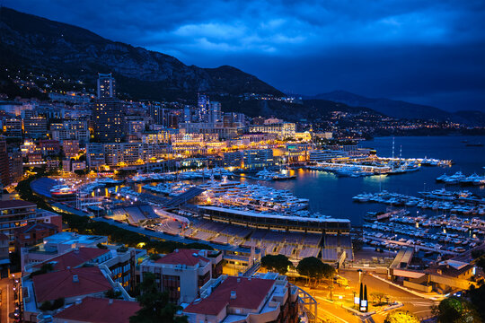 Aerial scene of Monaco Monte Carlo harbour and illuminated city skyline in the evening blue hour twilight. Monaco Port night view with luxurious yachts