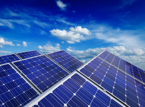Solar power generation technology, alternative renewable energy and environment protection ecology concept - close-up view of solar battery panels against blue sky with clouds