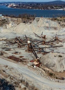 Aerial view of the Tompkins Cove Quarry featuring industrial machinery, conveyor belts, and large gravel piles set against the Hudson River landscape in Stony Point, New York, United States.