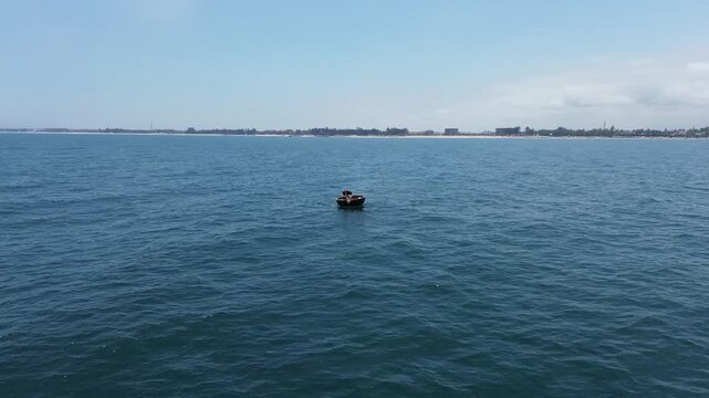 Vietnamese fisherman sailing alone on the open blue sea in a traditional round thung chai boat