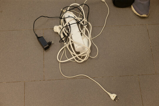a top-down view of untangled tangled electrical cords on a clean indoor floor, showcasing safety and organization in a cluttered home environment with white and red.