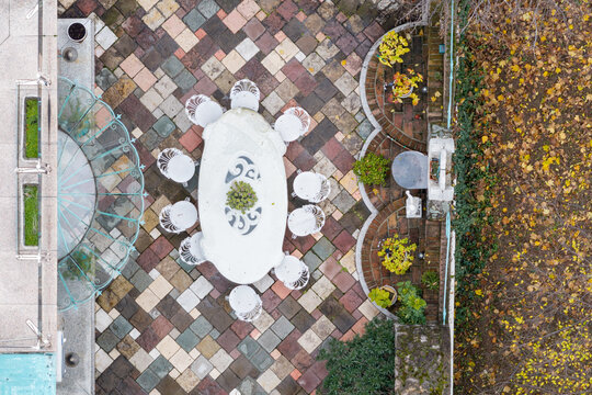 Aerial view of an outdoor dining area featuring a white oval table with chairs set on a multi-colored stone patio in Belgrade, Serbia.