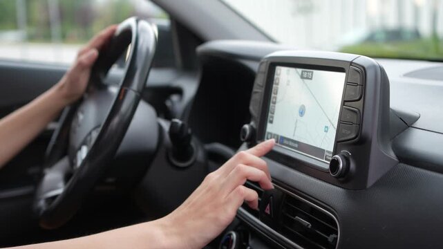 Close up of woman using the navigation system and touchscreen controls inside a car