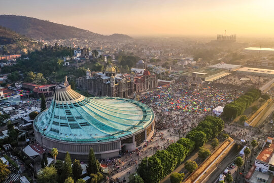 Aerial view of the Basilica of Our Lady of Guadalupe with its circular roof, surrounded by pilgrims in the plaza and historic buildings in Ciudad de Mexico, Ciudad de Mexico, Mexico.