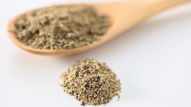 Small pile of whole black peppercorns on white background
