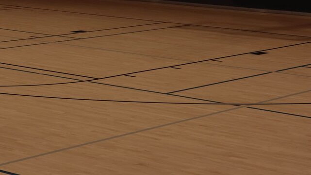 Steady right to left pan across an empty wooden basketball court.