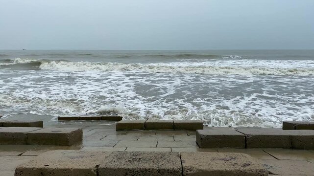 Overcast sky and violent sea waves crashing before hurricane storm