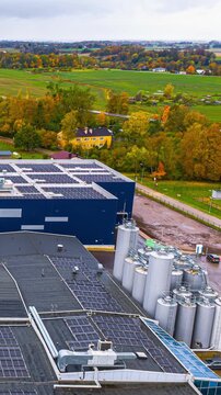 Timelapse aerial view of solar panels on industrial rooftops near countryside in autumn