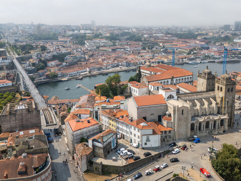 Aerial view of the historic Porto Cathedral and the Dom Luis I Bridge spanning the Douro River, surrounded by traditional terracotta rooftops in Porto, Porto, Portugal.