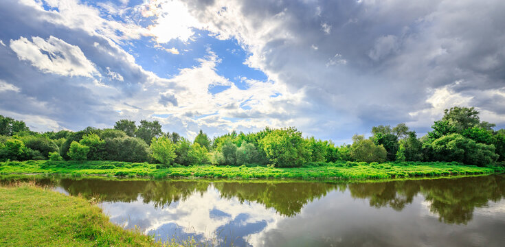 Serene river reflects dramatic clouds and thriving vegetation