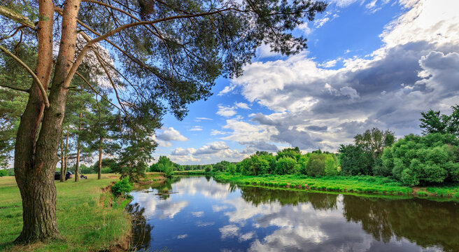 River glides quietly between verdant trees under partly cloudy sky