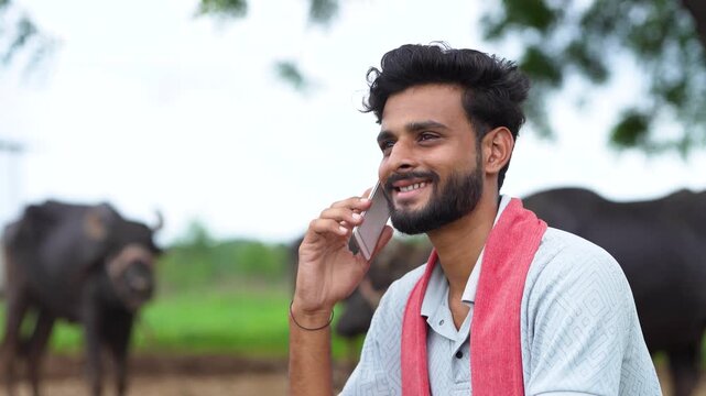 indian farmer talking on mobile phone at buffalo farm