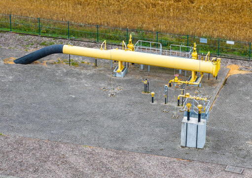 Aerial view of a yellow industrial gas pipeline section with valves and control equipment on a gravel surface in Slupsk, Pomeranian Voivodeship, Poland.
