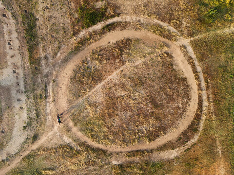 Aerial view of Arena Pacuan Kuda Tegalwaton featuring a circular dirt track surrounded by dry grassy fields in Kecamatan Tengaran, Jawa Tengah, Indonesia.