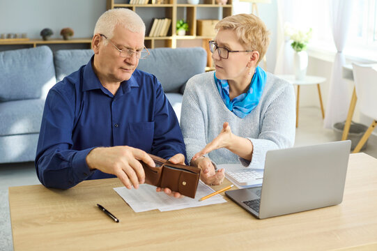 Seniors couple budgeting with empty wallet and bills. They discuss debt at a laptop, reviewing expenses, payments, and limited pension income. Financial stress in retirement concept.