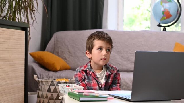 boy counts on his fingers in front of a laptop screen, remote classes. Online school. Homeschooling math. Early development of math skills. Mental arithmetic. E-learning