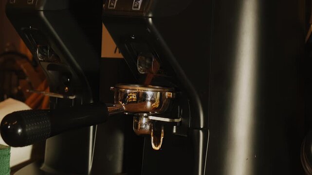 Barista fills portafilter with ground coffee from grinder in cafe closeup. Barkeeper prepares strong caffeine beverage with appliance in coffeeshop