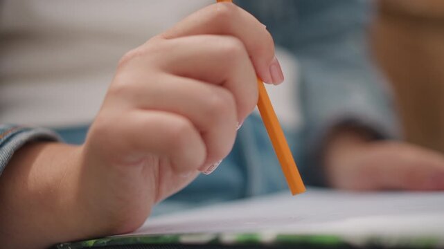 Sketching with pencil. Closeup of hand sketching. Focused image capturing hand and pencil in detail. Precise shot emphasizing hand gripping pencil among notebooks and background elements