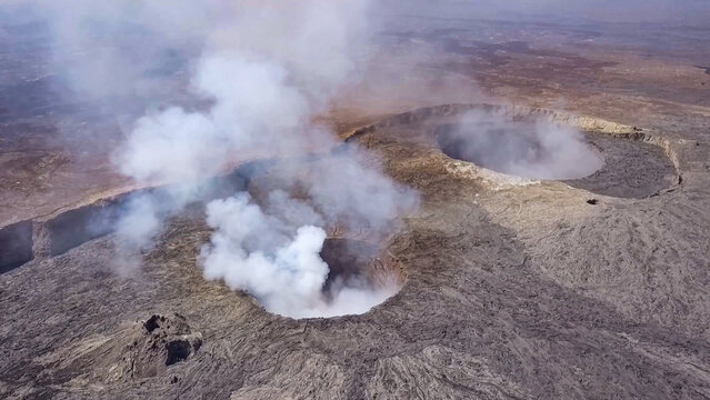 Aerial view of Erta Ale volcano with active lava lakes emitting thick white smoke over the rugged basaltic landscape in Zone 2, Afar, Ethiopia.