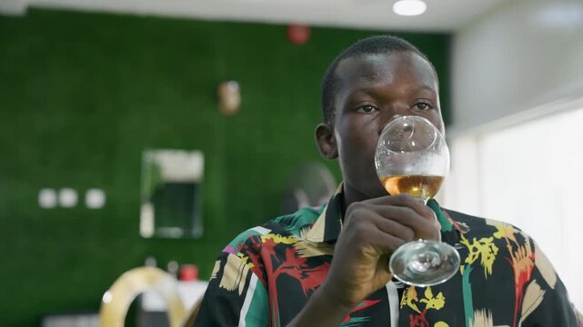 Person appreciating glass of wine. African American man carefully analyzing wine at dining table. Man of African descent thoughtfully inspecting and enjoying glass of wine during meal