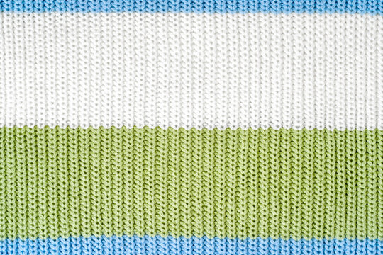 Close-up sweater texture in blue, white and pastel green colors, showing striped knitted surface. Concept of tactile textile detail, color rhythm and practical durable synthetic knitwear material