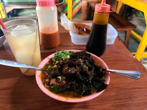 Indonesian Mie Ayam Bakso topping with wood ear mushrooms, served with iced drink and condiments.