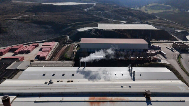 Aerial view of the building blocks factory and furnace with smoking chimneys, stacks of red bricks, and industrial roofs in Lugagnano Val D'arda, Emilia-Romagna, Italy.