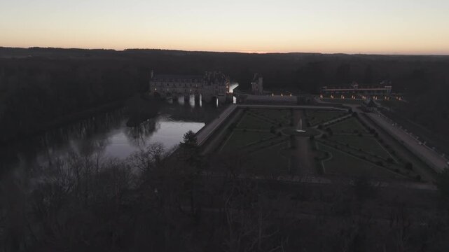An aerial view at dusk shows Chateau de Chenonceau and its geometric formal garden in the Loire Valley, France.