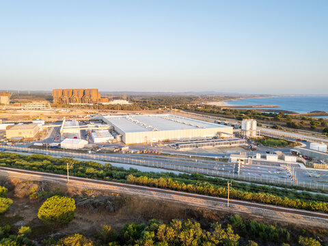 Aerial view of the hyperscale data center industrial facility and power plant infrastructure near the coastline with railway tracks and storage tanks in Sines, Setubal, Portugal.