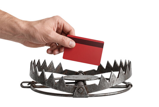Hand holding a red credit card over a steel animal trap