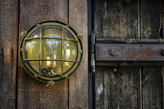Brass caged wall light beside rustic wooden door.