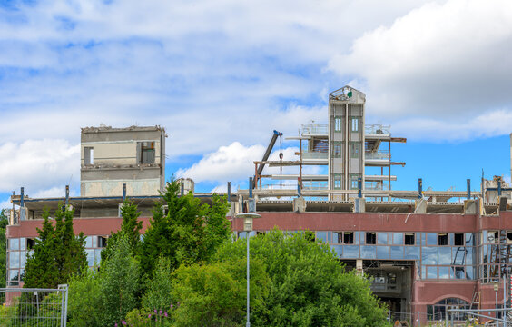 Partially demolished factory structure framed by summer vegetation.