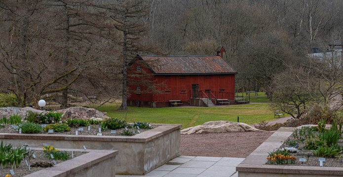 Historic red wooden house in peaceful botanical garden landscape.