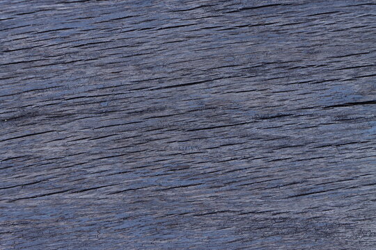 Texture of an old blue wooden board with cracks and peeling paint.