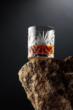 Crystal glass of whiskey resting on a piece of natural granite rock.