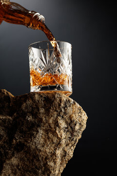 Whiskey is poured from a vintage bottle into a crystal glass.