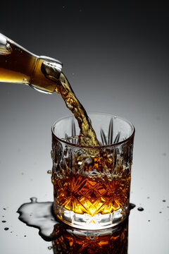 The amber-gold strong alcoholic beverage is poured into a crystal glass.