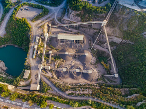 Aerial view of CCB Granulats Gaurain quarry with industrial processing machinery, conveyor belts, piles of gravel, and a turquoise water pond in Tournai, Wallonia, Belgium.