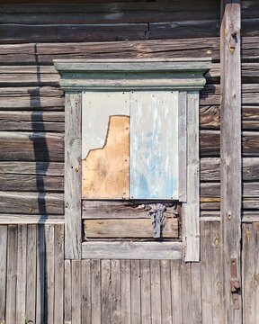 Abandoned weathered wooden window blocked with plywood