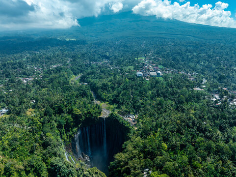 The breathtaking view of Tumpak Sewu Waterfall, surrounded by lush tropical forests in East Java, Indonesia.