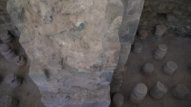 Ancient ruins near Garni temple. Exploring ancient stone pillars in a historical site in a remote area. Visitors look at stone pillars arranged in a circular pattern inside a historical structure. The