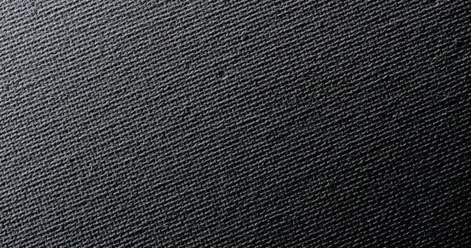 Black Woven Fabric Texture. Macro view of dark textile with fine diagonal weave and subtle shifting light.