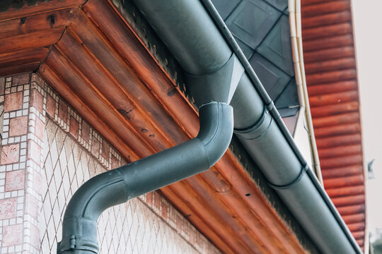 Building roof and wooden eave featuring a metal rain gutter system for proper water drainage and protection