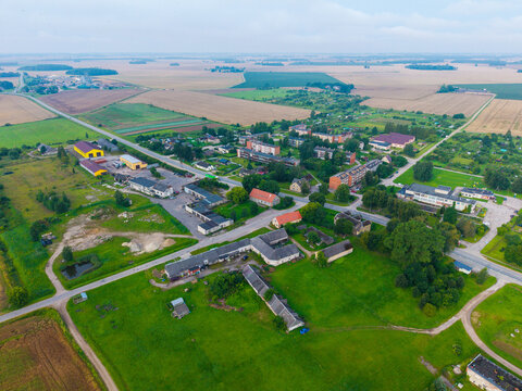 Aerial view of the rural village featuring residential buildings, agricultural fields, and green meadows in Jaunberze, Dobele Municipality, Latvia.