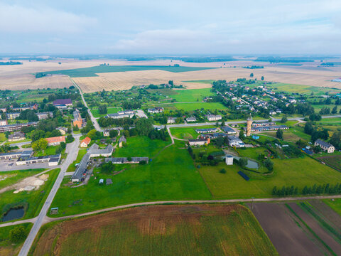 Aerial view of the rural village of Jaunberze with scattered houses, green fields, agricultural land, and a water tower in Jaunberze, Dobele Municipality, Latvia.